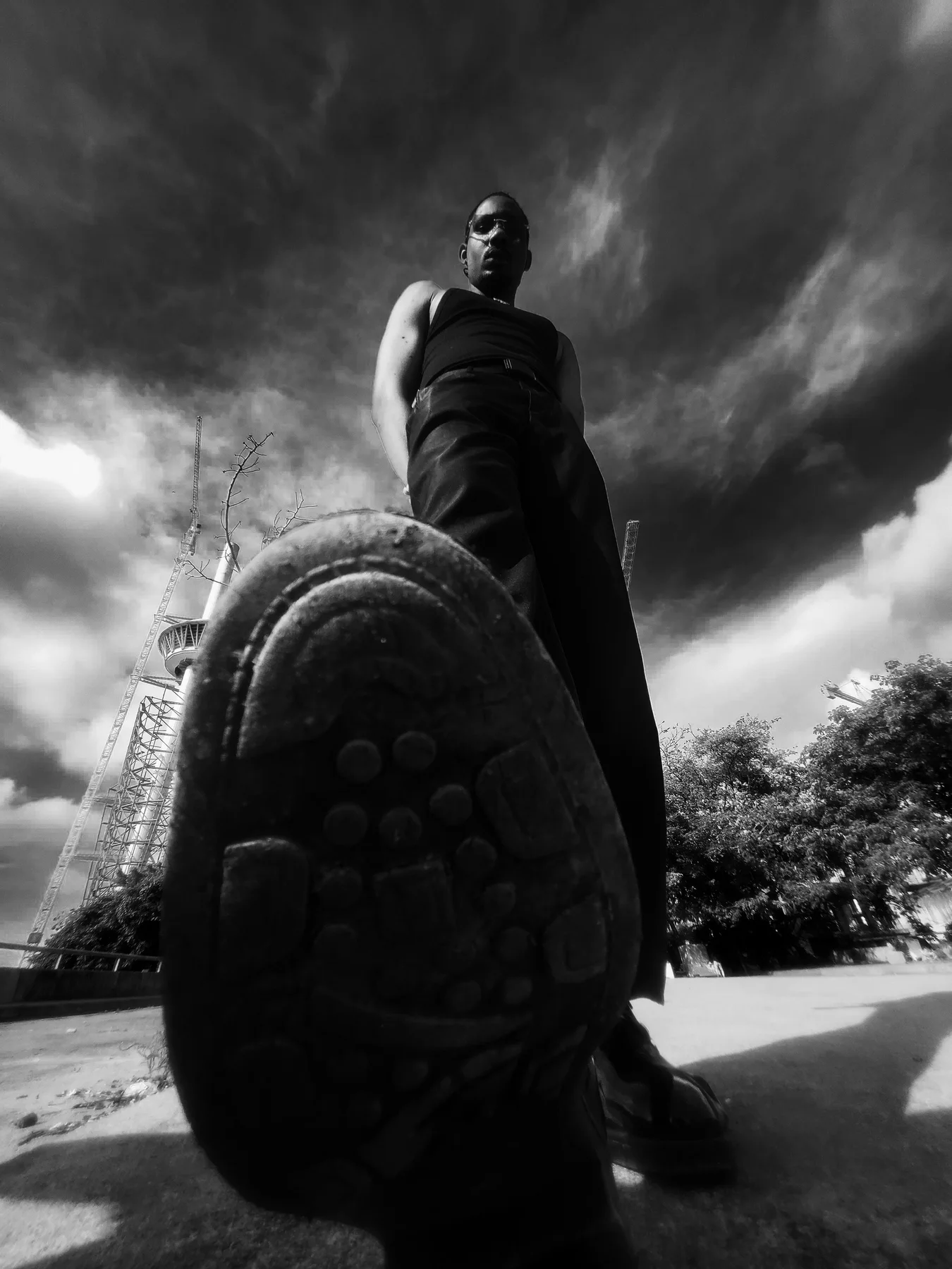 Homme en noir photographié en contre-plongée sous un ciel dramatique