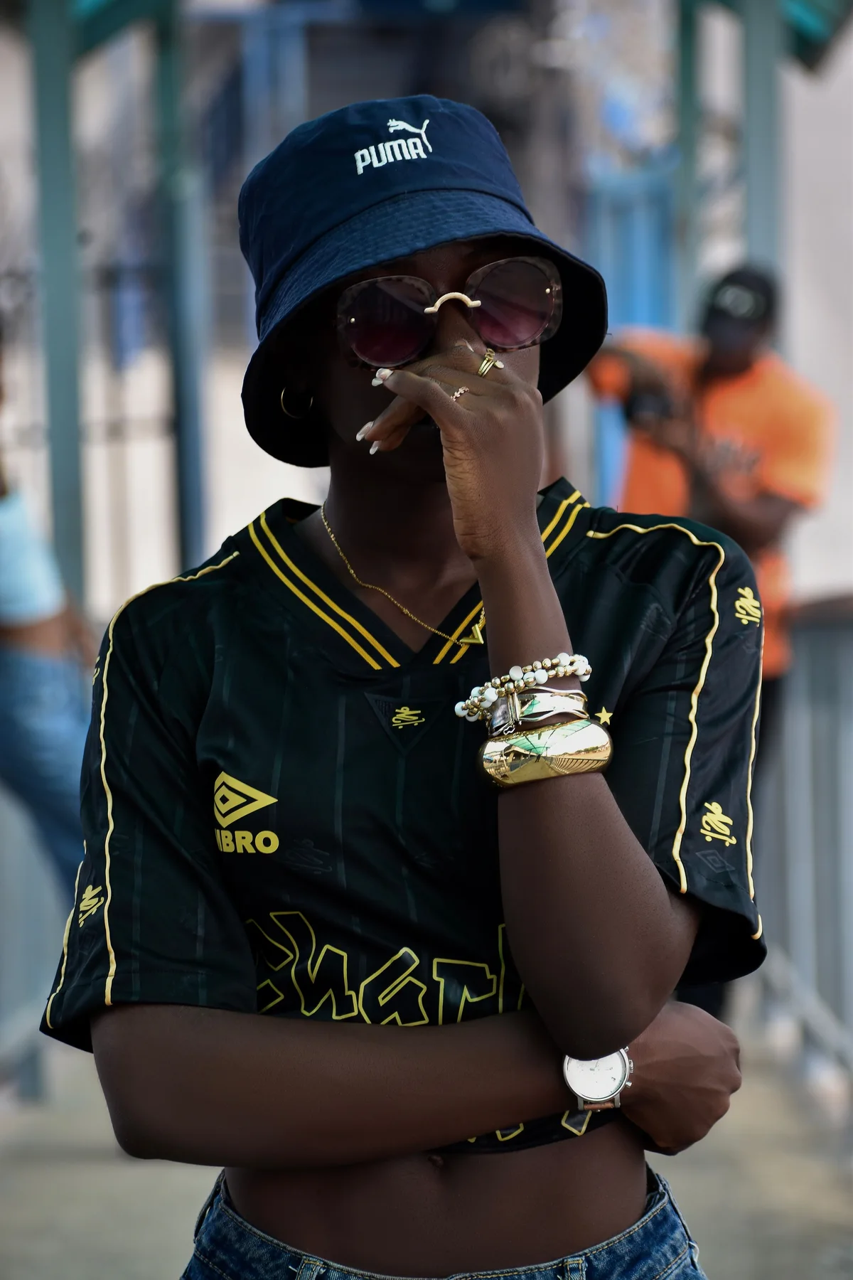 Femme portant un bob, des lunettes et des bijoux dans un portrait urbain
